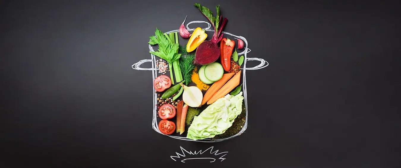 healthy produce set in a flat-lay on a blackboard inside a drawn pot