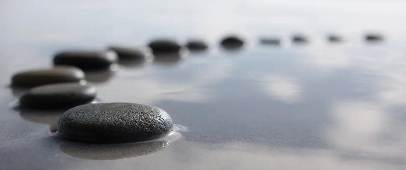 walking stone pebbles on calm water on a cloudy day