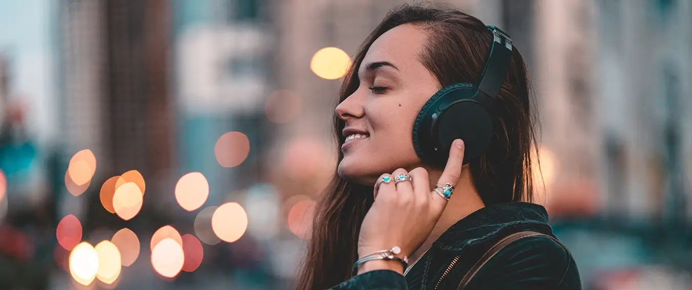 young woman listening to music on her headphones in the street