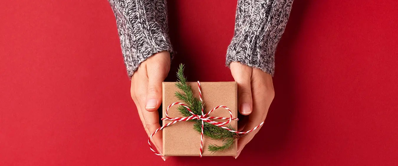 woman's hands holding a gift package over a red table