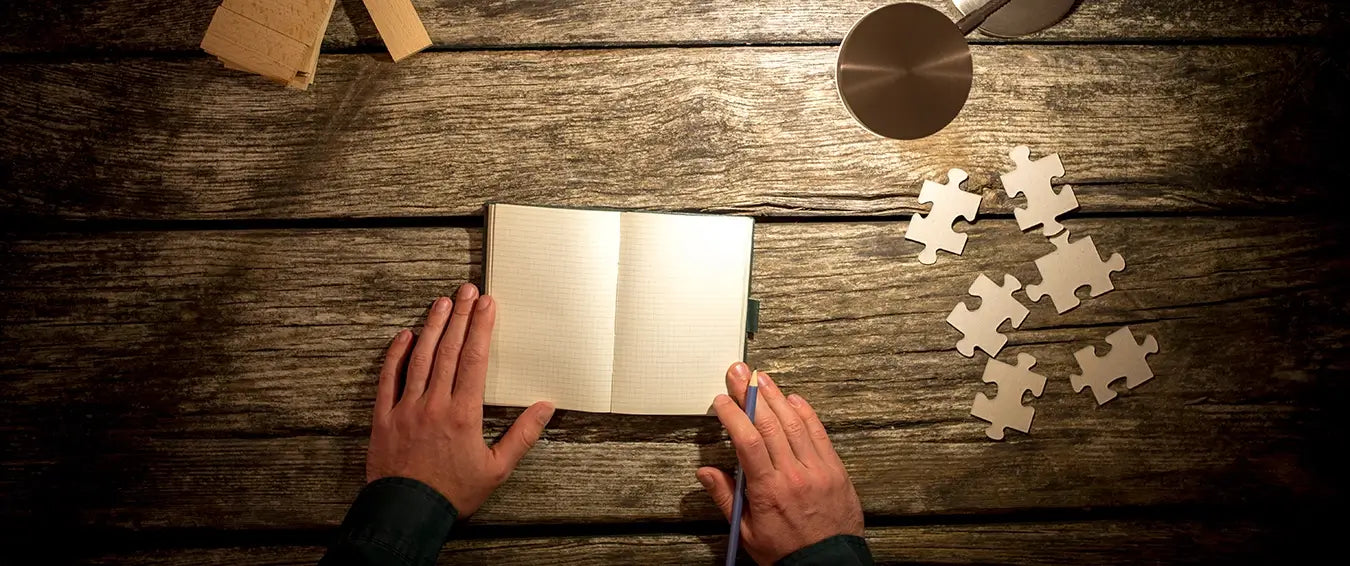 man getting ready to write on his gratitude journal on a wooden desk