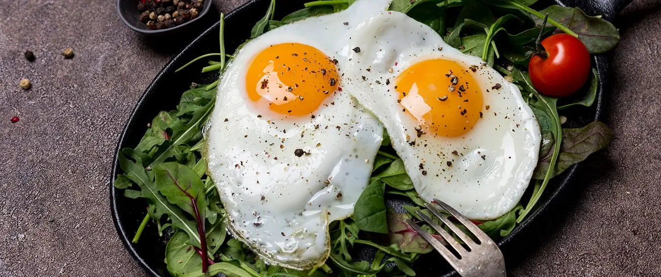 eggs sunny side up over greens in a pan