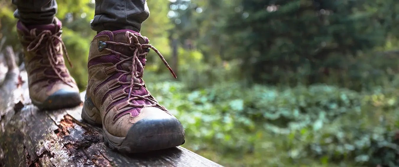 close-up of a walking hiker's boots on a tree trunk