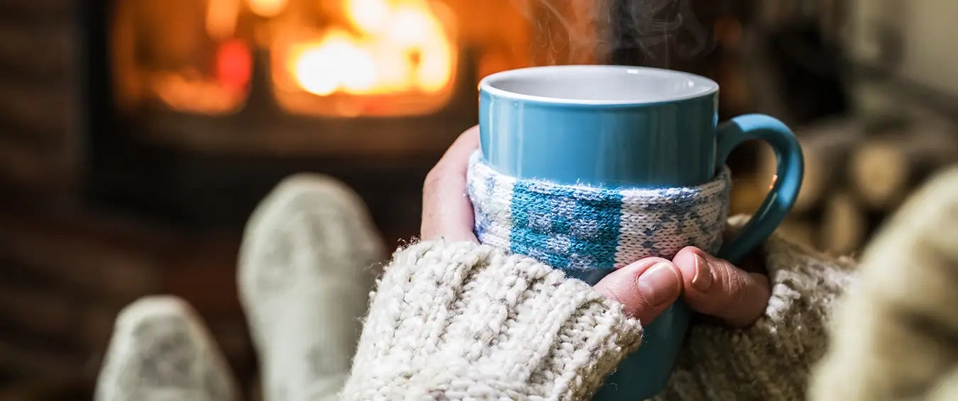 woman relaxing by the fire with a warm beverage