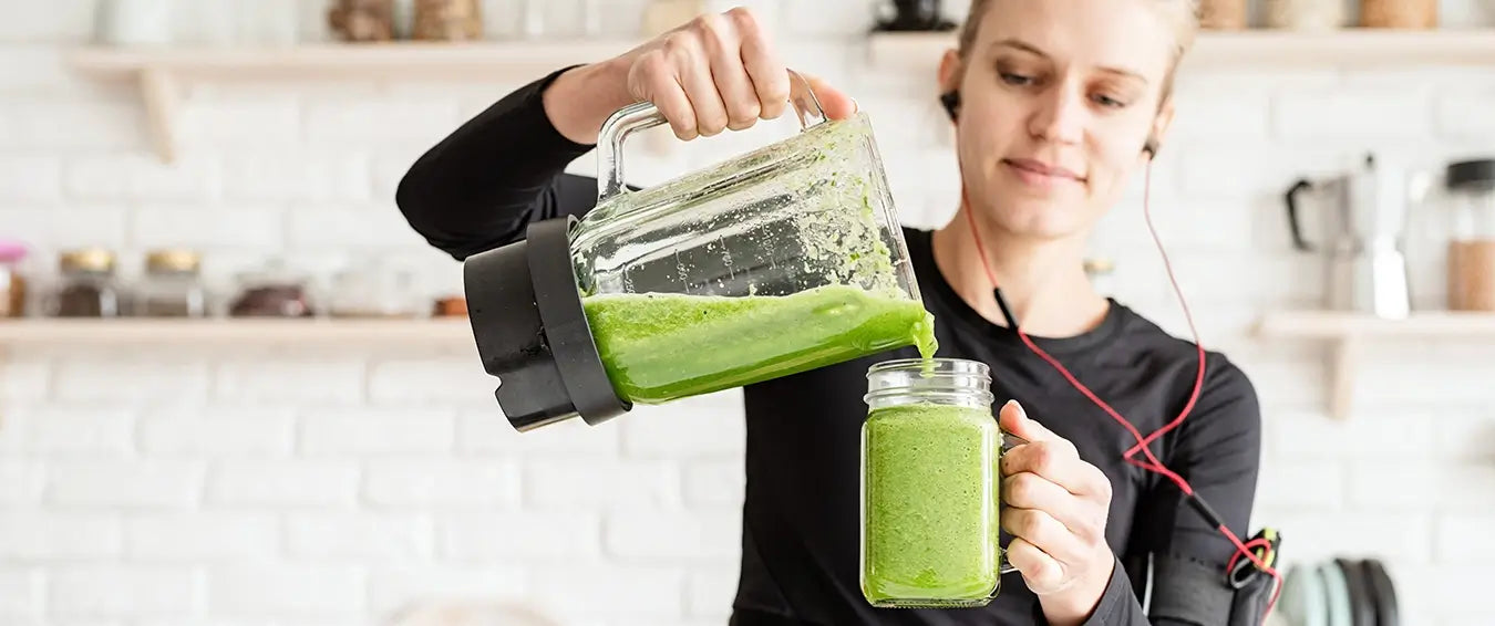 woman pouring a green smoothie into a mason jar