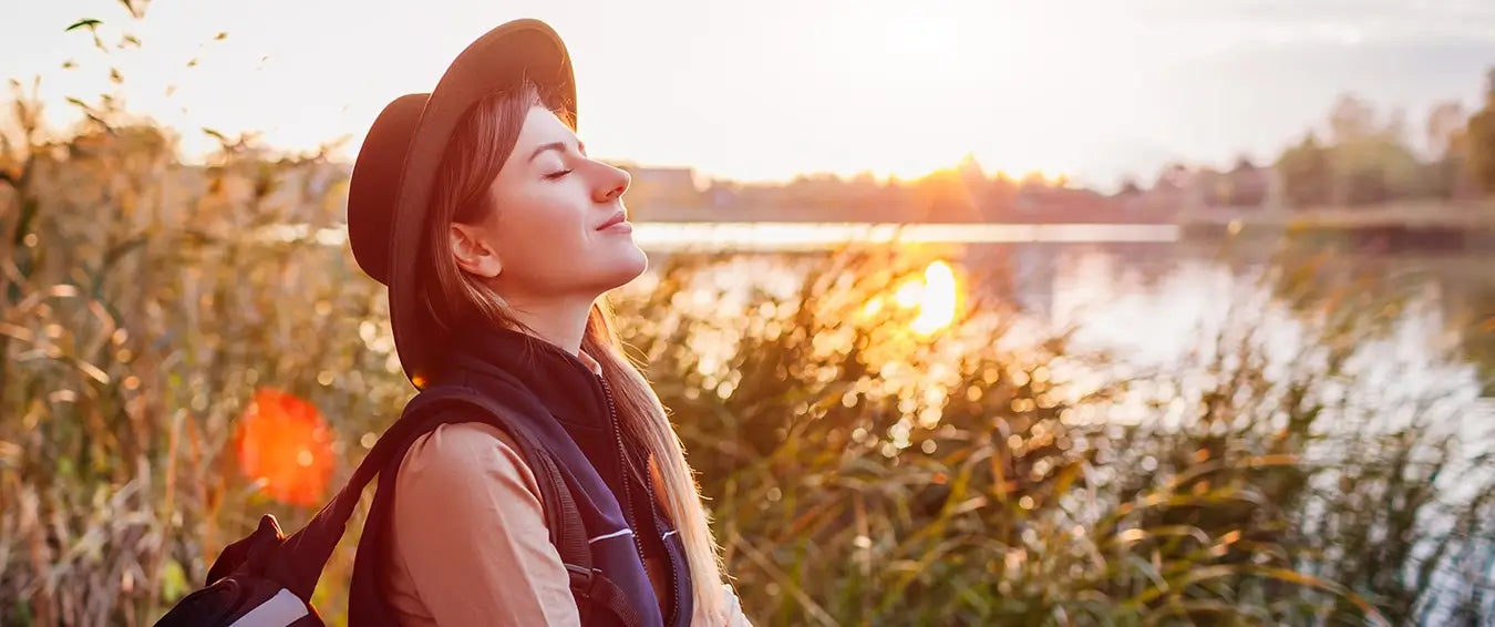 woman smiles during sunset with her eyes closes