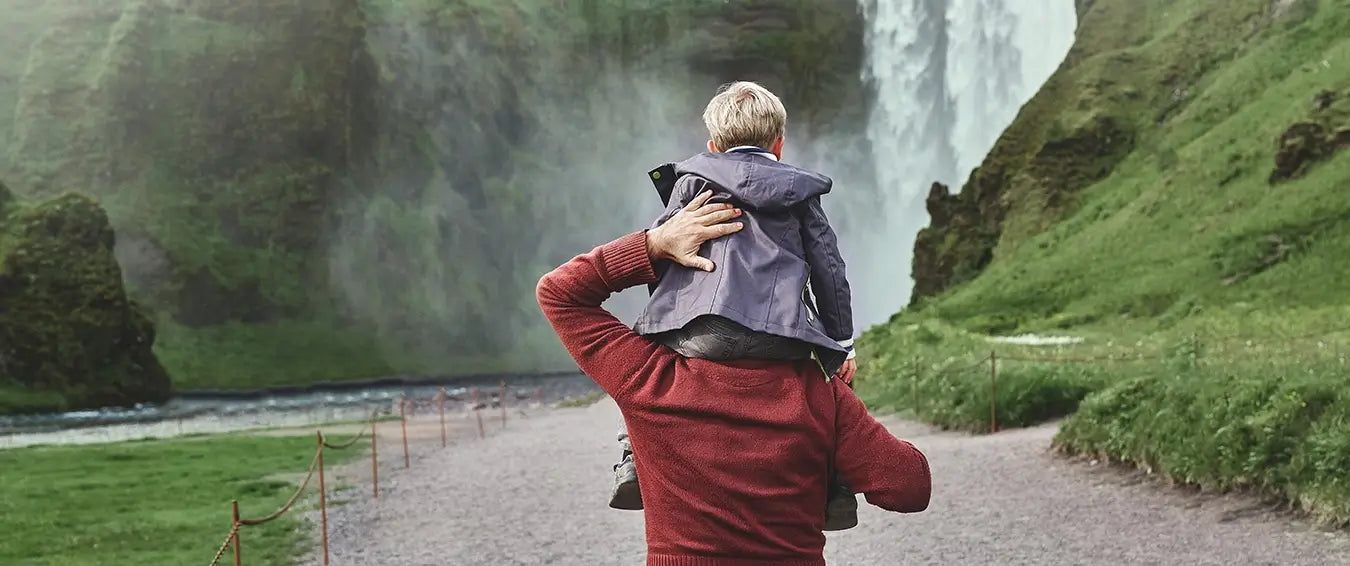 father carrying his toddler on his shoulders during a hike