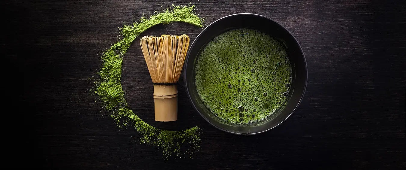 matcha powder in water in a bowl with a brush next to it