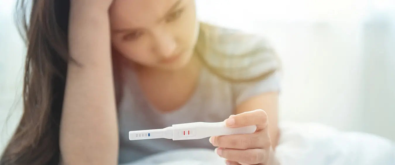 concerned young woman looking at the result of a pregnancy test