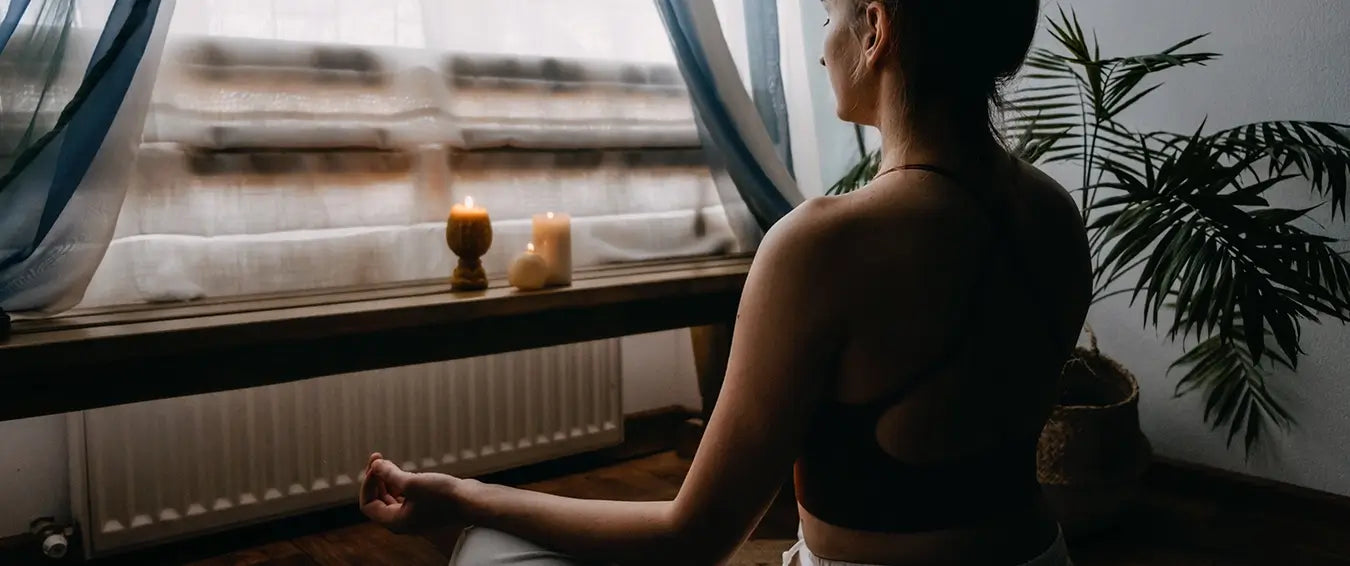 woman meditating in the afternoon with lit candles