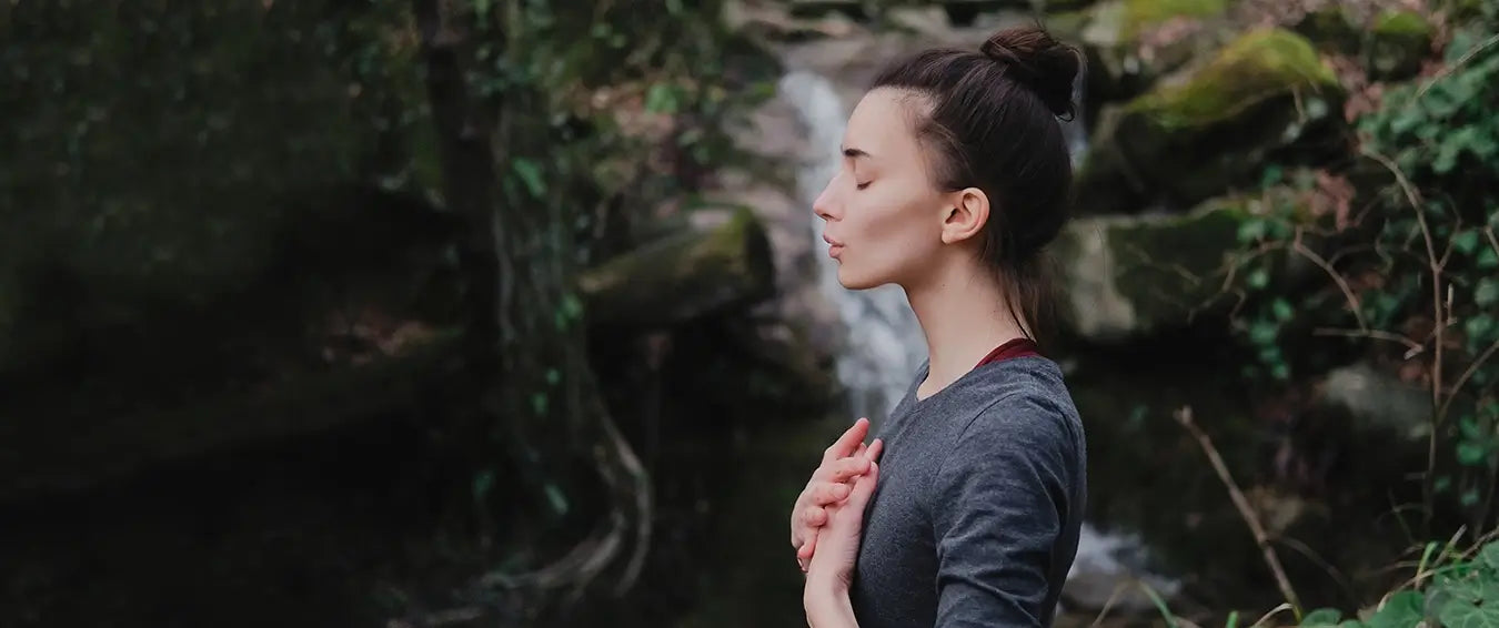 woman doing breathing exercise by a stream