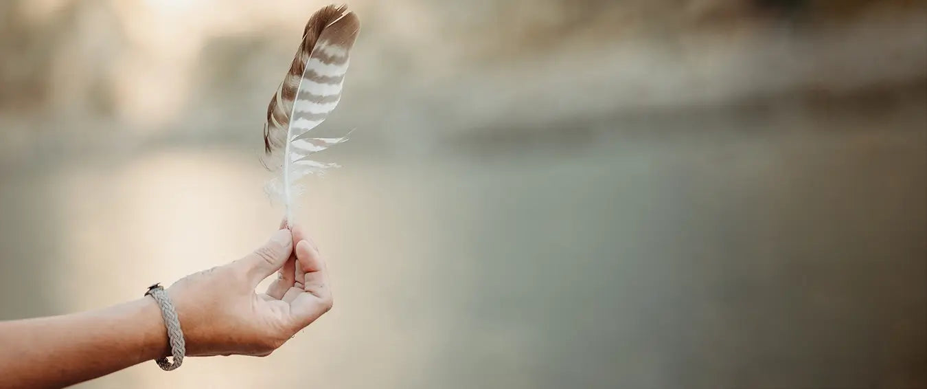 woman holding a feather in her hand on the beach