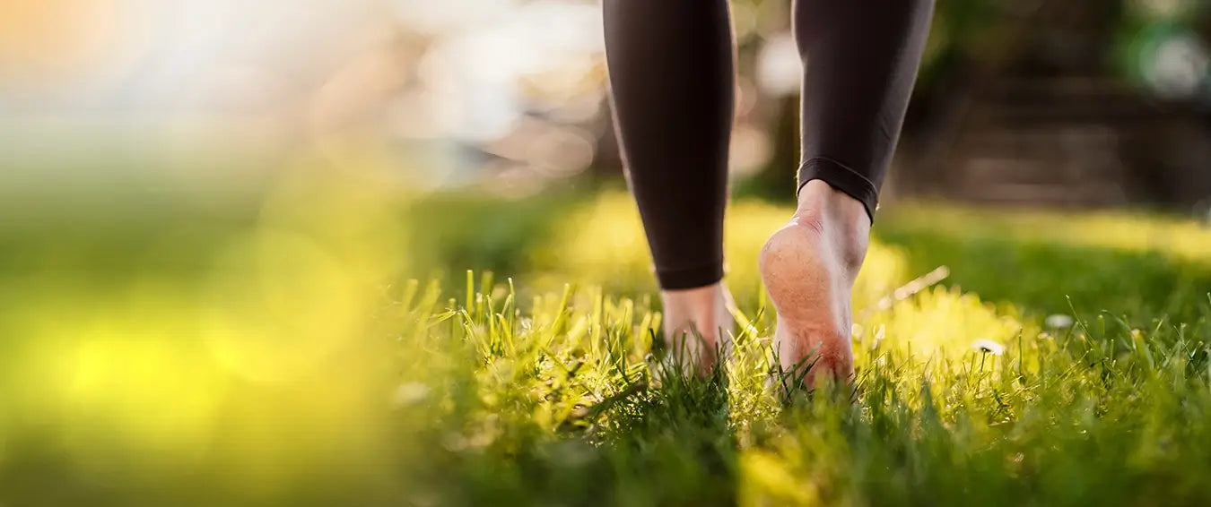 close of the feet of woman walking on grass